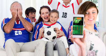 Composition of woman using smartphone with sports app over family of football fans. sport and...