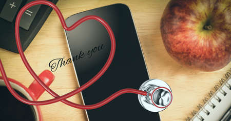 Composition of thank you text on smartphone with heart shaped stethoscope. medicine, healthcare services and gratitude concept digitally generated image.の写真素材