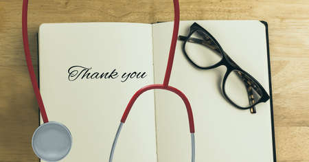 Composition of thank you text on notebook with stethoscope and glasses. medicine, healthcare...