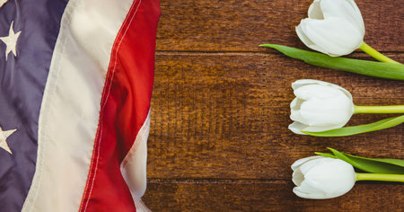 American flag and white tulip flowers on wooden background. american patriotism template background design conceptの写真素材