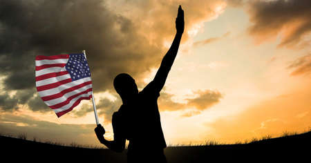 Composition of silhouette person with american flag over sunset sky. patriotism, independence and celebration concept digitally generated image.の写真素材
