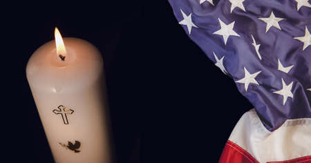 Composition of american flag and lit candle with christian cross on black. patriotism, independence and celebration concept digitally generated image.の写真素材