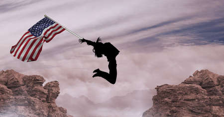 Composition of silhouetted figure jumping holding american flag against mountains and cloudy sky. patriotism, independence and celebration concept digitally generated image.の写真素材