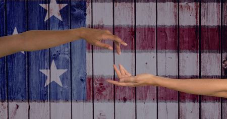 Composition of two diverse female arms reaching out over american flag painted on wood. patriotism, independence and celebration concept digitally generated image.の写真素材
