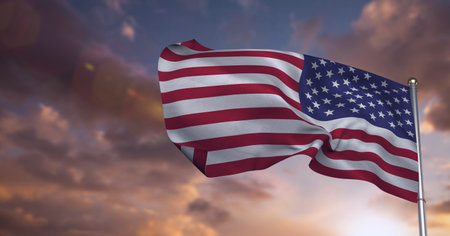 Composition of american flag on flag pole billowing over sunset sky. patriotism, independence and celebration concept digitally generated image.の写真素材