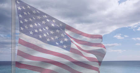 Composition of billowing american flag on flagpole over sea and cloudy blue sky. patriotism,...