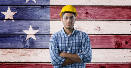 Composition of portrait of male construction worker over american flag painted on wooden boards. patriotism, independence and labor day celebration concept digitally generated image.の写真素材