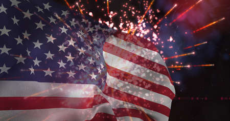 Composition of american flag billowing over fireworks in night sky. patriotism, independence and celebration concept digitally generated image.の写真素材
