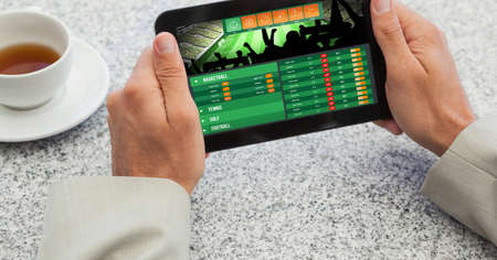 Close up of hand holding digital tablet against coffee cup on the table. digital interface and modern technology conceptの写真素材