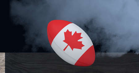 Canada flag on rugby ball over wooden surface against smoke effect on black background. sports tournament and competition conceptの写真素材