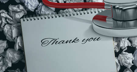Thank you text and stethoscope over diary against crumbled paper balls in background. healthcare love and support conceptの写真素材