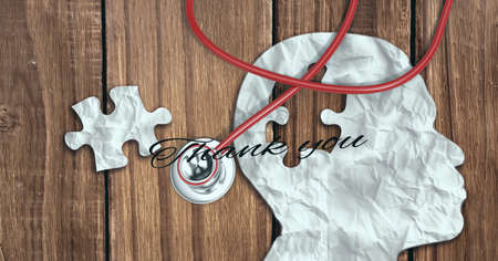Thank you text, stethoscope and human face puzzle cutout against wooden background. healthcare love and support conceptの写真素材