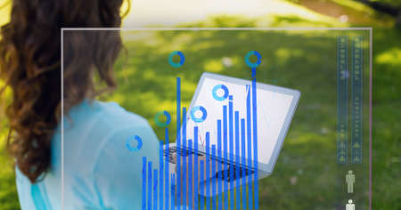 Digital interface with statistical data processing against woman using laptop in the garden. computer interface and business technology conceptの写真素材