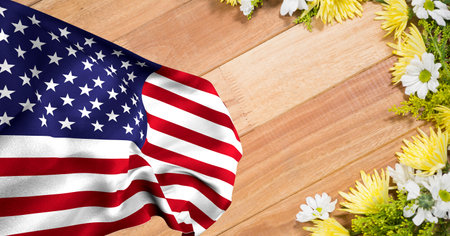 Waving american flag against white and yellow flowers on wooden background. american patriotism...