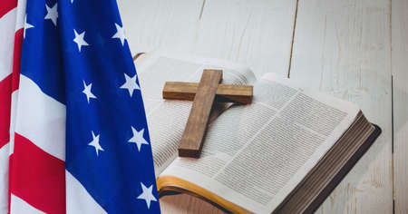 American flag over wooden cross over bible against wooden background. american patriotism and religion template background design conceptの写真素材