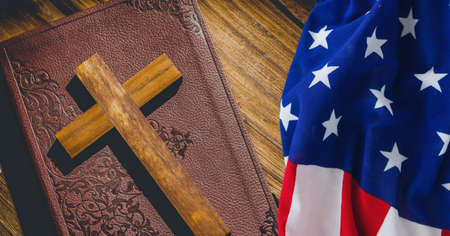 American flag over wooden cross over bible against wooden background. american patriotism and religion template background design conceptの写真素材