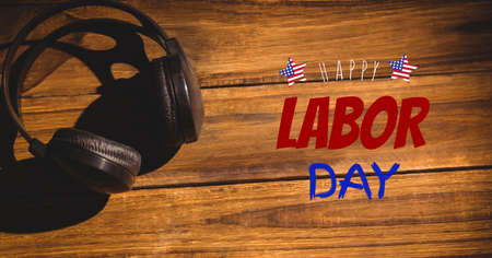 Happy labor day text against headphone on wooden background. american labor day template background design conceptの写真素材