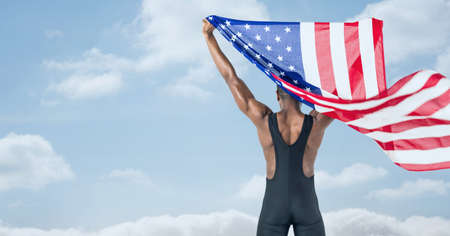 Composition of male athlete holding waving american flag against clouds on blue sky. united states patriotism and independence concept digitally generated image.の写真素材