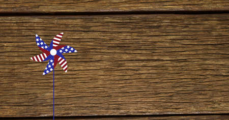 Composition of windmill coloured with american flag over wooden table. american patriotism, independence and celebration concept digitally generated image.の写真素材