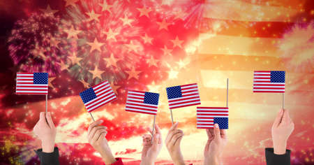 Composition of hands holding american flags over fireworks. american patriotism, independence and celebration concept digitally generated image.の写真素材