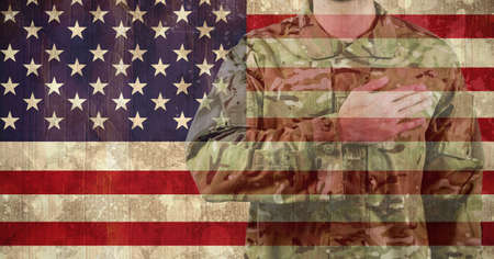 Composition of midsection of male soldier with hand on heart, against american flag. patriotism, independence and military concept digitally generated image.の写真素材
