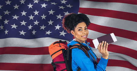 Composition of smiling woman holding passport and ticket, over waving american flag. patriotism,...
