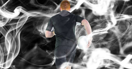 Composition of male rugby player holding rugby ball on black background. sport and competition concept digitally generated image.の写真素材