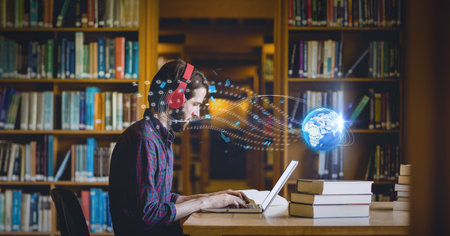 Composition of digital globe over male student using laptop in library. global education, digital...