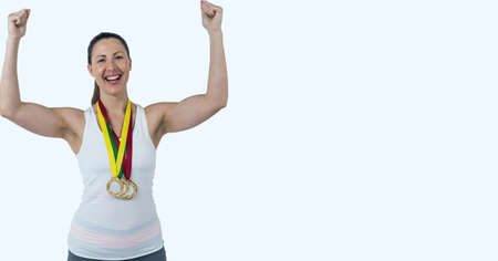 Portrait of caucasian woman with many medals around her neck celebrating against white background. sports competition and tournament conceptの写真素材