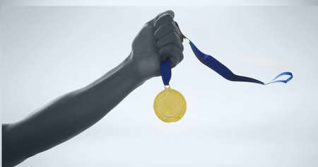 Black and white image of close up of hand holding a medal against grey background. sports tournament and competition conceptの写真素材
