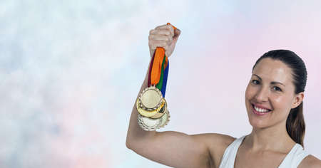 Portrait of caucasian female athlete holding multiple medals smiling against smoke effect background. sports tournament and competition concepの写真素材