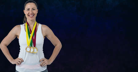 Portrait of caucasian woman with many medals around her neck smiling against blue background. sports...