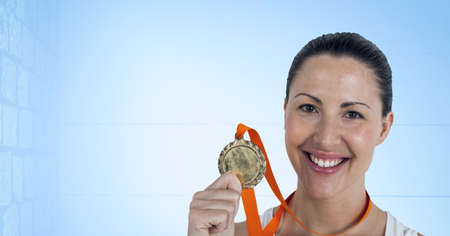 Portrait of caucasian female athlete holding a medal around her neck smiling against blue background. sports tournament and competition conceptの写真素材