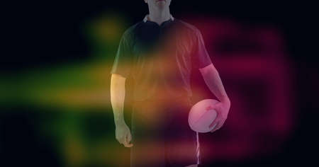 Composition of glowing yellow and red blur over male rugby player holding rugby ball, on black. sport and competition digitally generated imageの写真素材