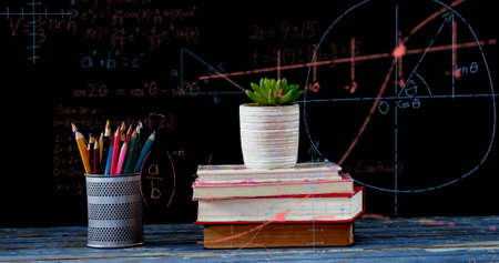 Image of mathematical equations floating over books, plant and coloured pencils on black background....