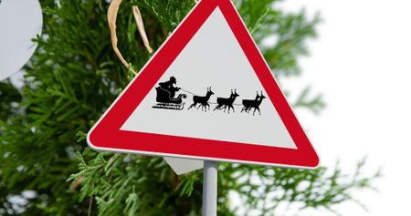 Digital image of santa claus in sleigh being pulled by reindeers on signboard against christmas tree on white background. christmas festivity celebration tradition conceptの写真素材