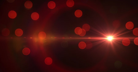 Image of glowing red spots of flickering bokeh light floating hypnotically with lens flare on a dark...