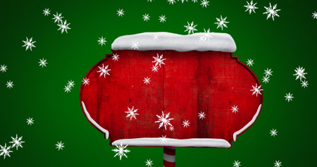 Digital image of snowflakes falling over red wooden sign post against green background. christmas festivity celebration tradition conceptの写真素材