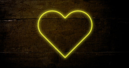 Image of yellowneon heart flashing on dark wood background. valentines day, love and romance concept, digitally generated image.の写真素材