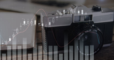Digital image of graphs moving in the screen with a background of a gadgets in a table and a vintage film camera 4kの写真素材