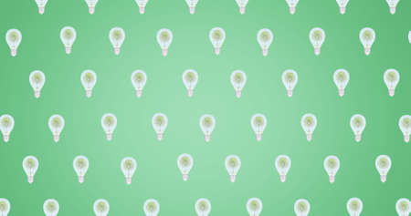 Composition of multiple trees in light bulbs repeated in grid over green background. global conservation and earth day concept digitally generated image.の写真素材