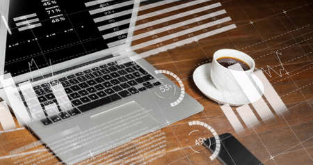 Statistical data processing against laptop and coffee cup on wooden surface. global finance and business conceptの写真素材