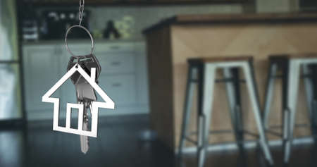 Image of silver house keys and house shaped key fob hanging over an out of focus open plan kitchen 4kの写真素材