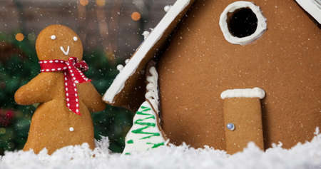 Image of christmas gingerbread snowman and house with snow falling. christmas celebration festivity concept digitally generated image.の写真素材