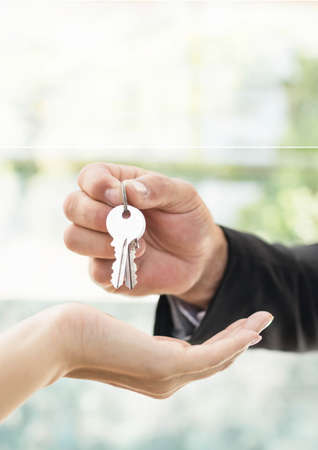 Close up of real estate agent giving keys house to customer. property and real estate conceptの写真素材