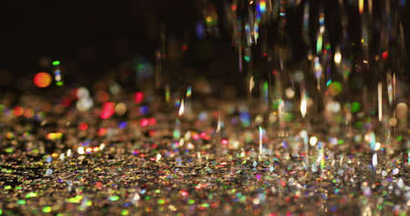 Multicoloured glitter gems falling on black background. christmas new year's eve party festivity...