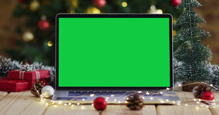 Laptop with green screen on screen, with christmas decorations and tree. christmas, festivity and communication technology digital composite image.の写真素材