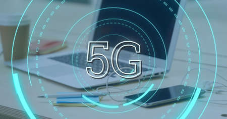Digital image of futuristic circles moving around 5G with background of   a desk with a cup of...