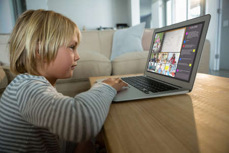 Caucasian boy using laptop for video call, with smiling diverse elementary school pupils on screen....