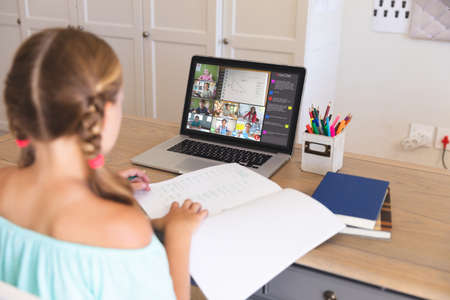 Caucasian girl using laptop for video call, with diverse elementary school pupils on screen. communication technology and online education, digital composite image.の写真素材